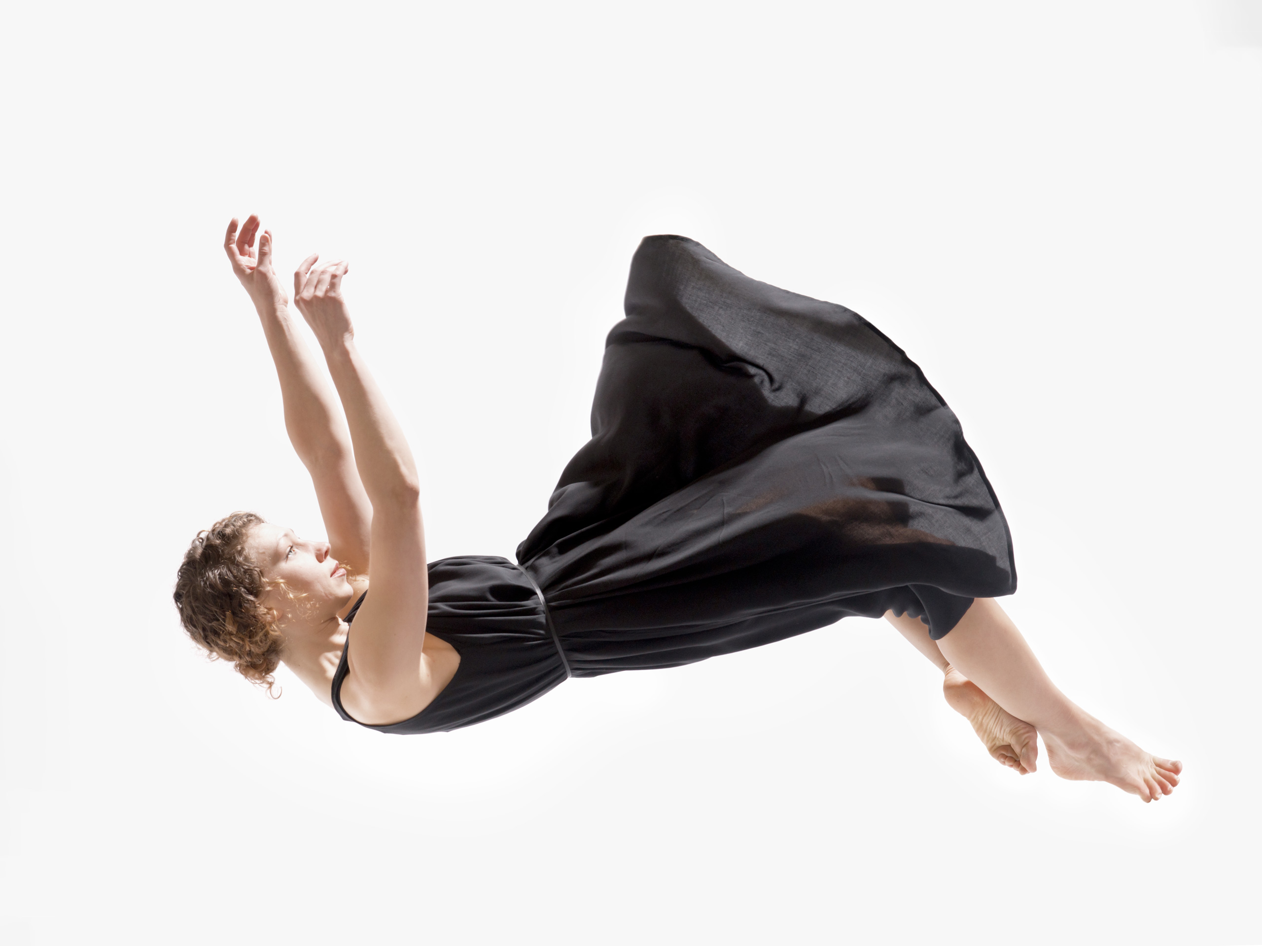 push/FOLD dancer Jessica Evans falls through the air wearing an elegant black dress on a white background in 'November' | Photography: David Krebs