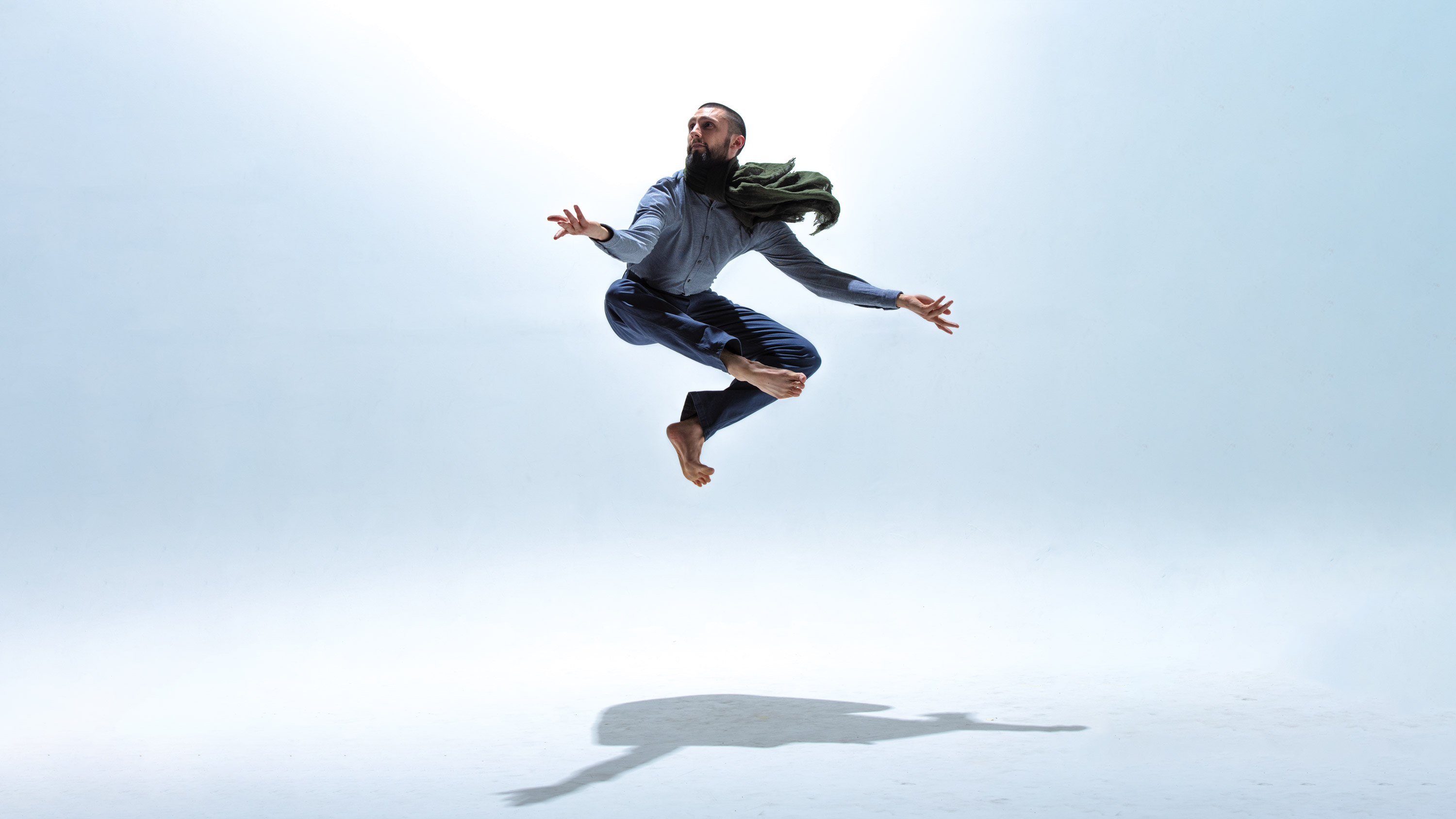push/FOLD's artistic director Samuel Hobbs leaps high in a green scarf with legs tucked underneath at Cobalt Studios in Portland, Oregon | Photography: Jingzi Zhao